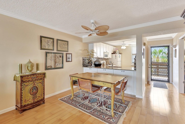 dining space featuring crown molding, light hardwood / wood-style flooring, and a textured ceiling