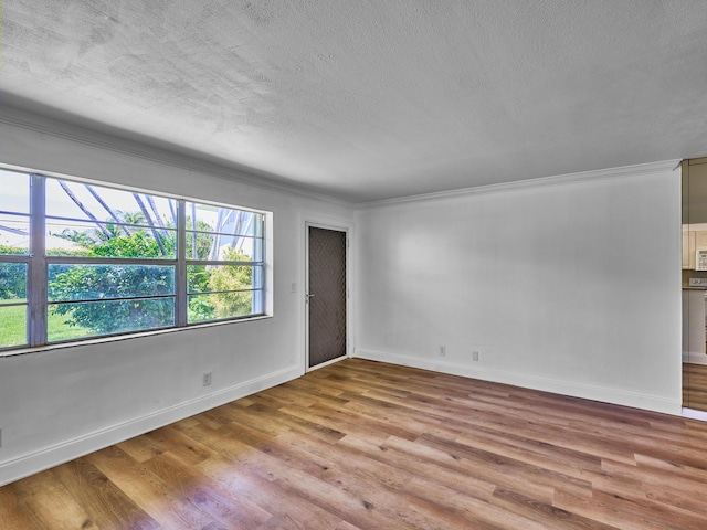 empty room with light hardwood / wood-style floors, ornamental molding, and a textured ceiling