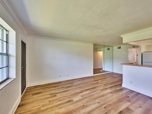 spare room with light wood-type flooring and ornamental molding