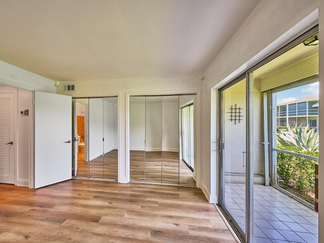 unfurnished bedroom featuring light hardwood / wood-style floors and multiple closets