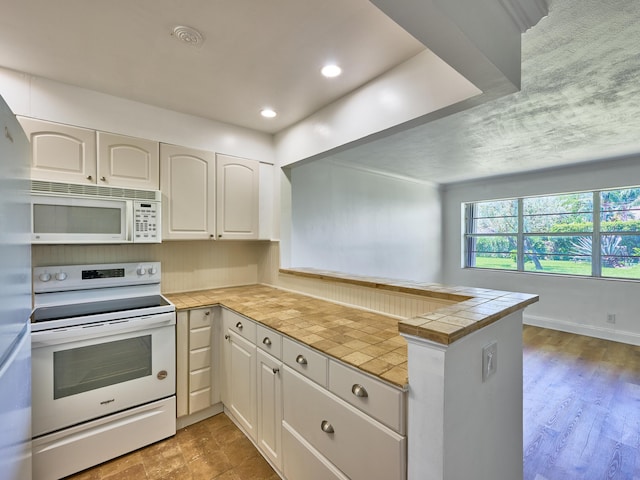 kitchen featuring kitchen peninsula, tile countertops, white cabinets, and white appliances