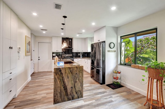 kitchen featuring hanging light fixtures, light hardwood / wood-style floors, an island with sink, and appliances with stainless steel finishes