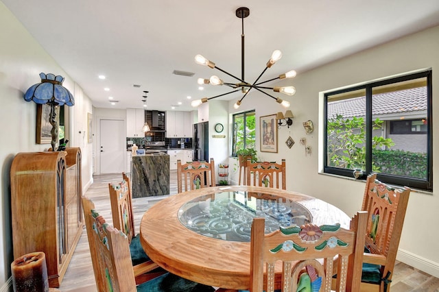 dining area with light hardwood / wood-style flooring and an inviting chandelier