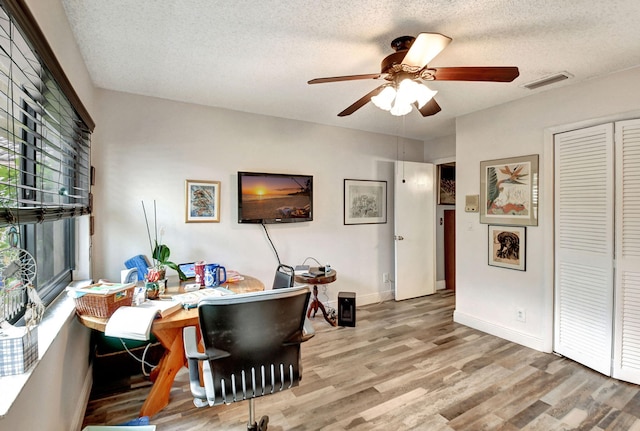 office space featuring light hardwood / wood-style floors, ceiling fan, and a textured ceiling