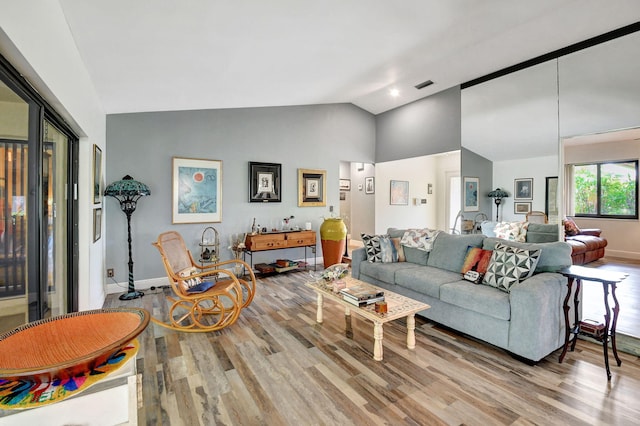 living room with high vaulted ceiling and light hardwood / wood-style flooring