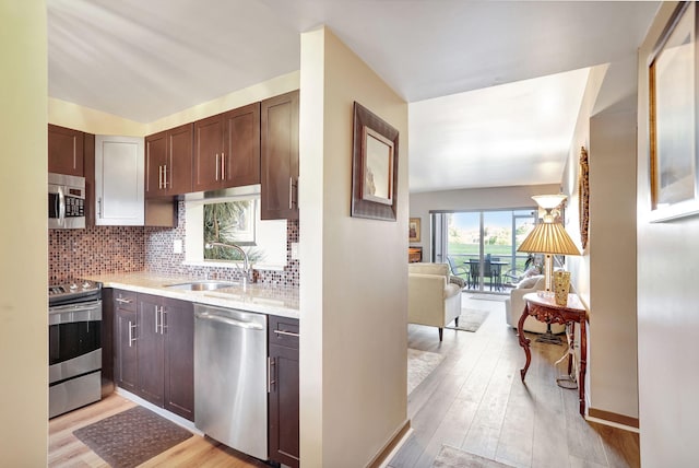 kitchen featuring decorative backsplash, dark brown cabinetry, stainless steel appliances, sink, and light hardwood / wood-style floors