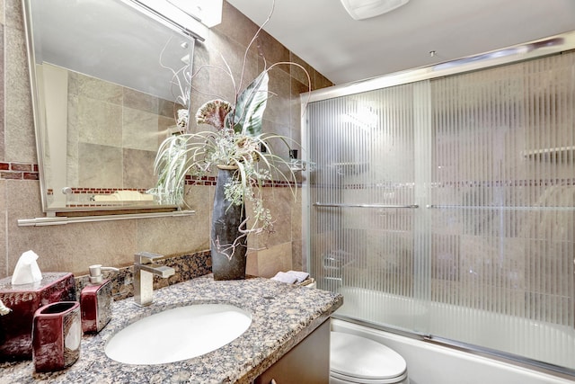 full bathroom with vanity, enclosed tub / shower combo, tile walls, and toilet