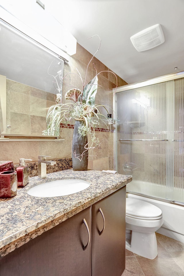 full bathroom featuring tile patterned floors, vanity, toilet, and combined bath / shower with glass door