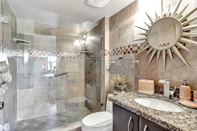 bathroom with an enclosed shower, vanity, toilet, and tile walls