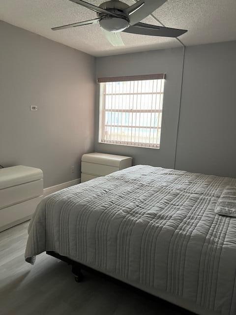 bedroom featuring ceiling fan, a textured ceiling, and light hardwood / wood-style floors