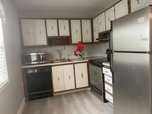 kitchen featuring light hardwood / wood-style floors, sink, white cabinetry, and black appliances