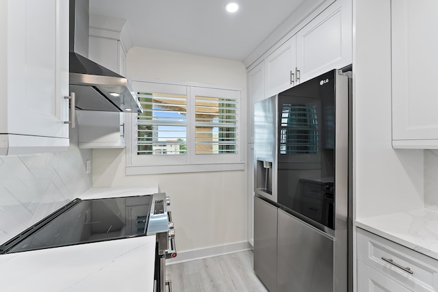 kitchen featuring high end fridge, light hardwood / wood-style flooring, white cabinets, wall chimney range hood, and backsplash