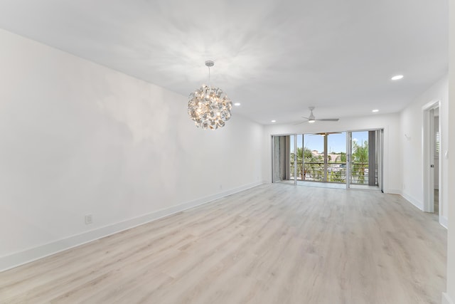 unfurnished room featuring ceiling fan with notable chandelier and light hardwood / wood-style flooring