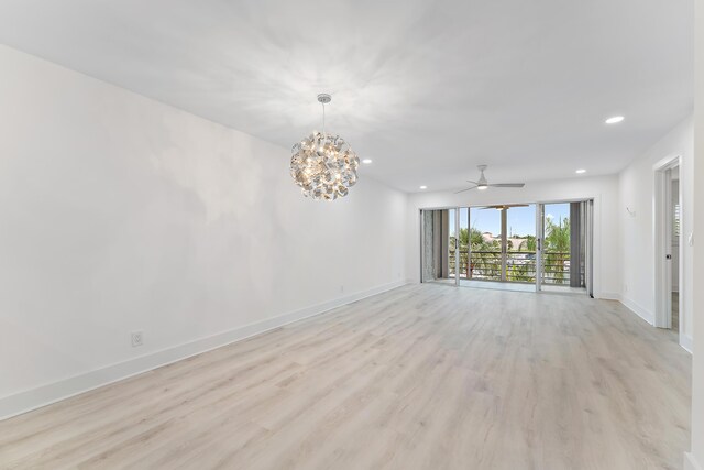 spare room featuring ceiling fan with notable chandelier and light hardwood / wood-style floors