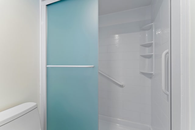 bathroom featuring tiled shower and toilet