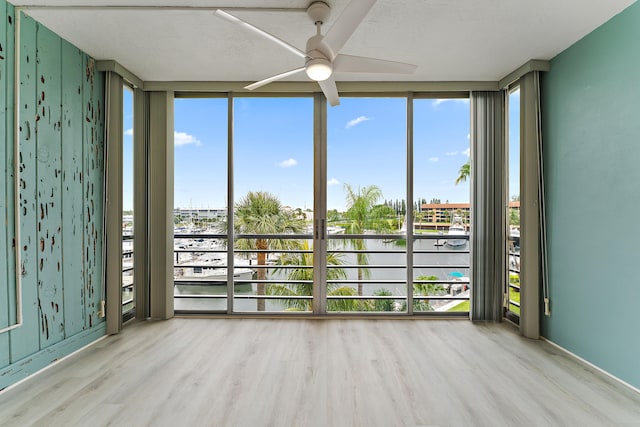 empty room with ceiling fan, light hardwood / wood-style flooring, and floor to ceiling windows