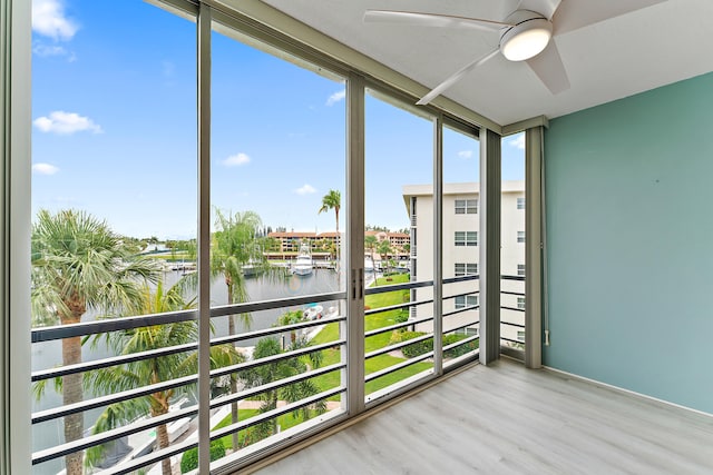 unfurnished sunroom with plenty of natural light, a water view, and ceiling fan