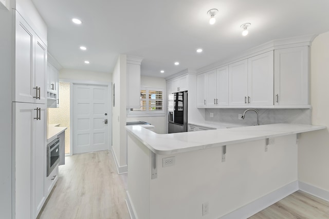 kitchen with kitchen peninsula, white cabinetry, stainless steel fridge with ice dispenser, and light hardwood / wood-style floors