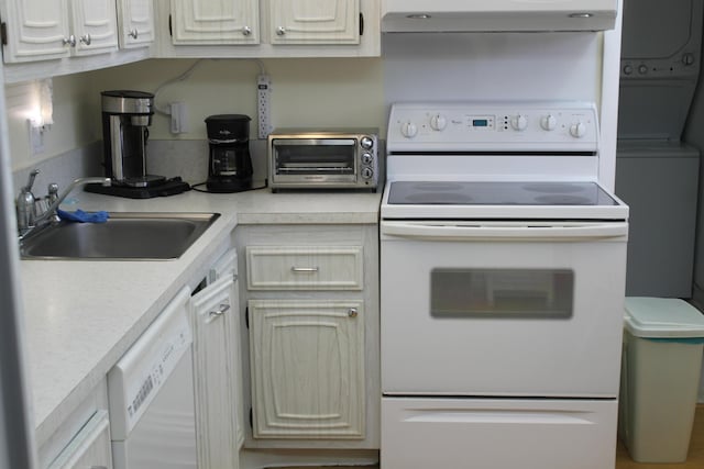 kitchen with extractor fan, stacked washing maching and dryer, sink, and white appliances