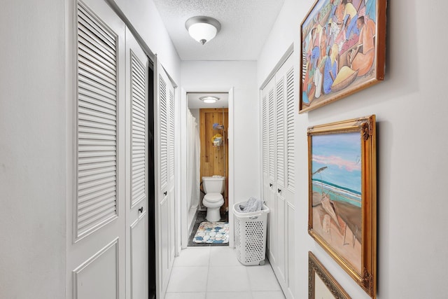 hallway featuring a textured ceiling and light tile floors