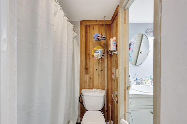 bathroom with wood walls, vanity, and toilet