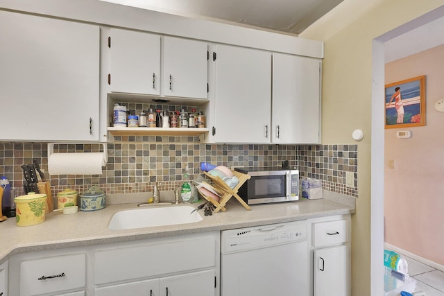 kitchen featuring sink, dishwasher, white cabinets, and backsplash