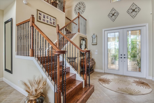 tiled entrance foyer featuring a towering ceiling and french doors