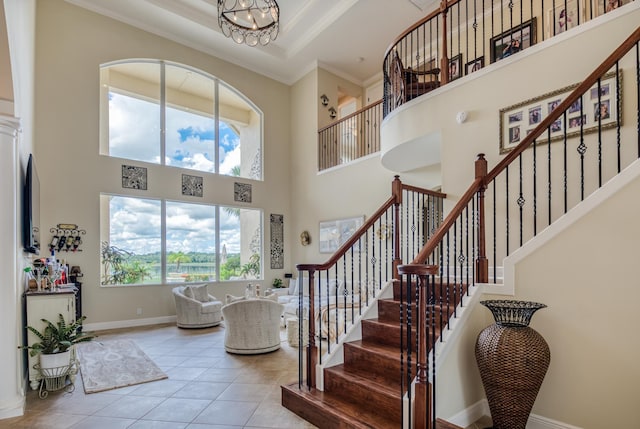 entryway featuring a high ceiling, ornamental molding, light tile patterned floors, and an inviting chandelier