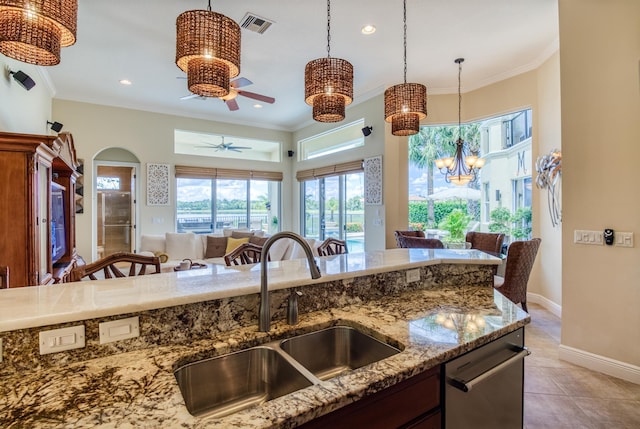 kitchen with sink, decorative light fixtures, light stone countertops, and light tile patterned floors