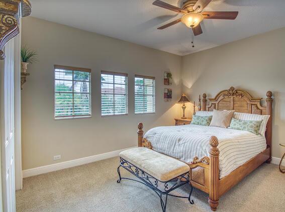 bedroom with multiple windows, light colored carpet, and ceiling fan