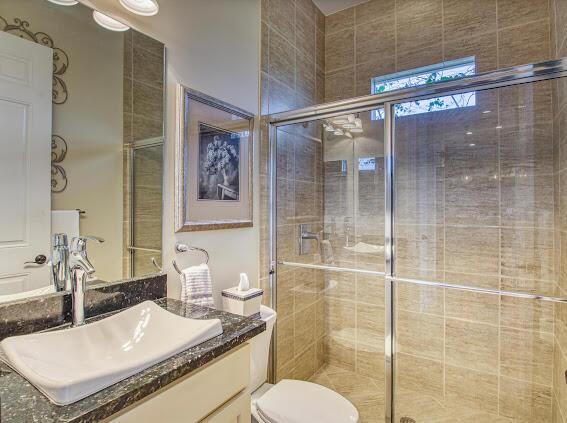 bathroom featuring an enclosed shower, vanity, and toilet