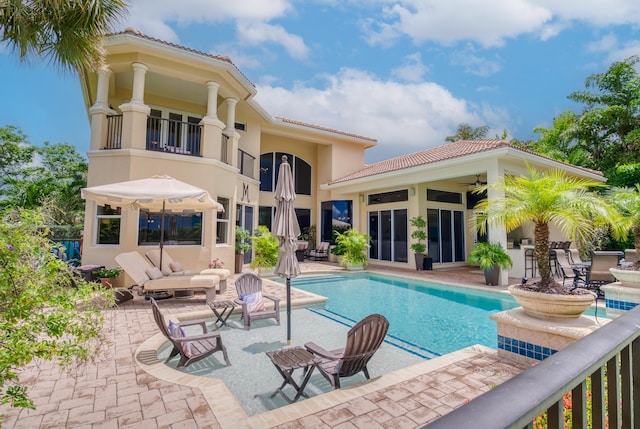 rear view of property with a balcony, ceiling fan, and a patio area