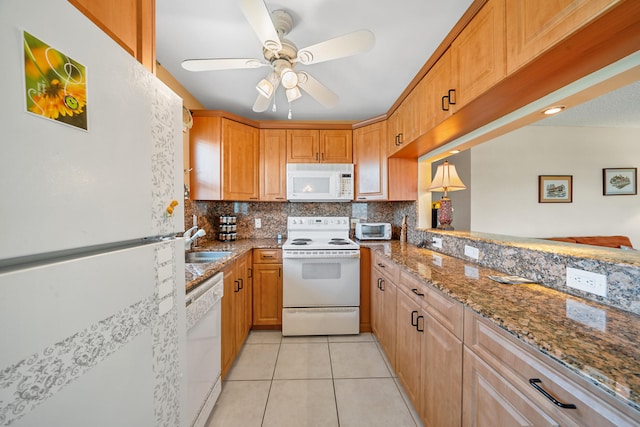 kitchen featuring tasteful backsplash, white appliances, stone counters, light tile floors, and sink