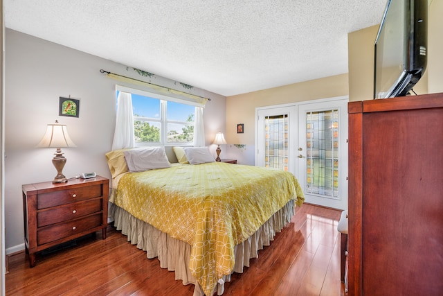 bedroom featuring wood-type flooring, access to exterior, a textured ceiling, and french doors