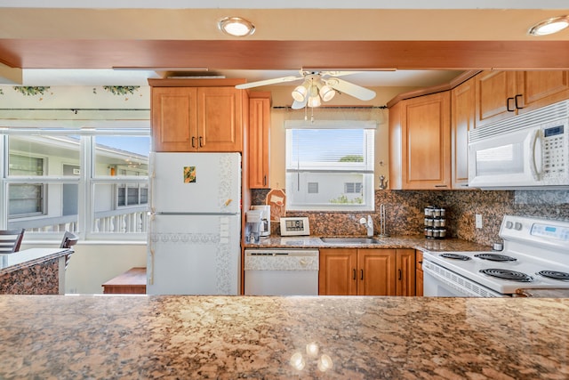 kitchen with ceiling fan, white appliances, light stone counters, backsplash, and sink