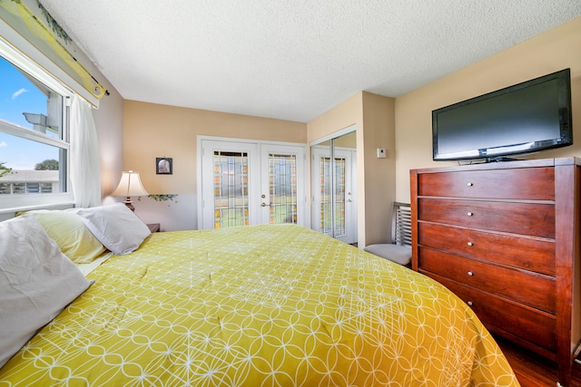 bedroom with french doors, a textured ceiling, and access to outside