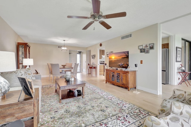 living room featuring a textured ceiling, light tile patterned floors, and ceiling fan