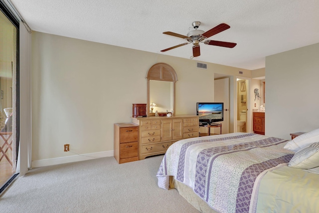 carpeted bedroom with a textured ceiling, ensuite bathroom, and ceiling fan