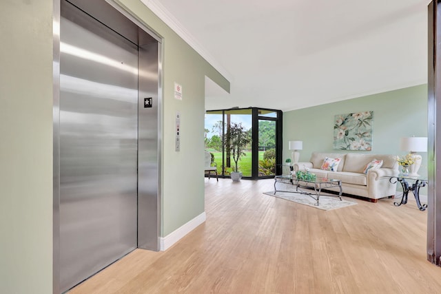 living room featuring ornamental molding, light hardwood / wood-style flooring, elevator, and floor to ceiling windows