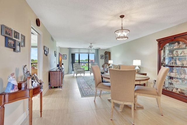 tiled dining room featuring a textured ceiling and ceiling fan with notable chandelier