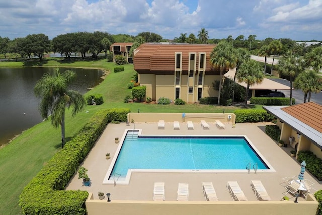 view of pool with a patio, a water view, and a lawn