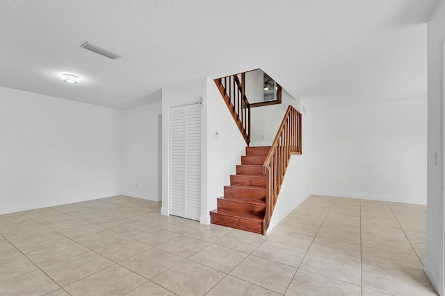 stairs with tile patterned flooring and a textured ceiling