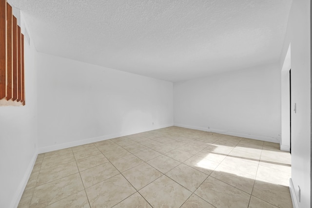 spare room featuring a textured ceiling and light tile patterned flooring