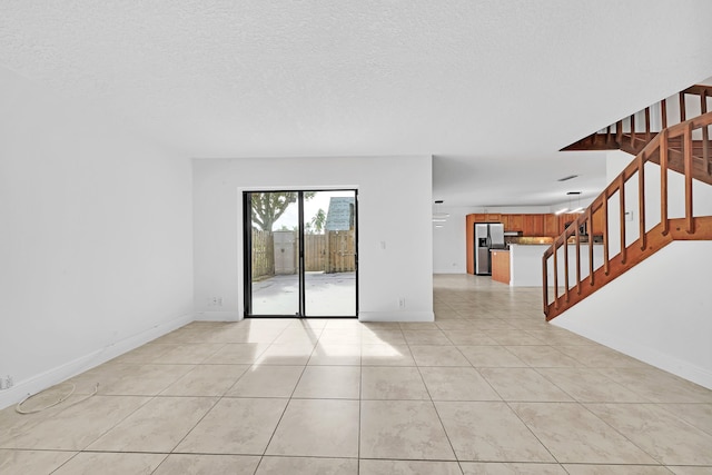 spare room with a textured ceiling and light tile patterned floors