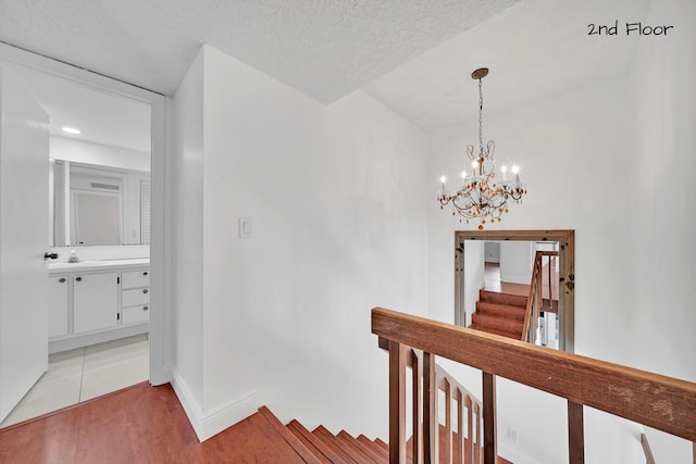 stairs with hardwood / wood-style floors, a notable chandelier, and a textured ceiling