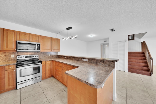 kitchen with pendant lighting, kitchen peninsula, appliances with stainless steel finishes, and a textured ceiling