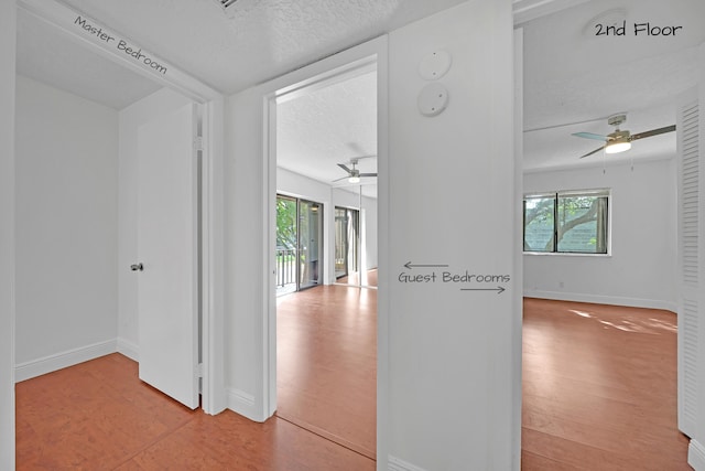 hall featuring a textured ceiling and light hardwood / wood-style floors