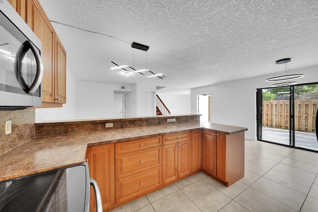 kitchen with a chandelier, kitchen peninsula, appliances with stainless steel finishes, and hanging light fixtures