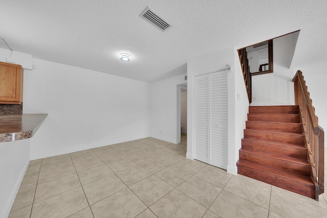 interior space with a textured ceiling and tile patterned floors