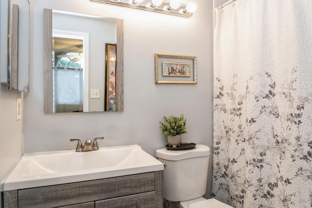 bathroom with walk in shower, vanity, and toilet